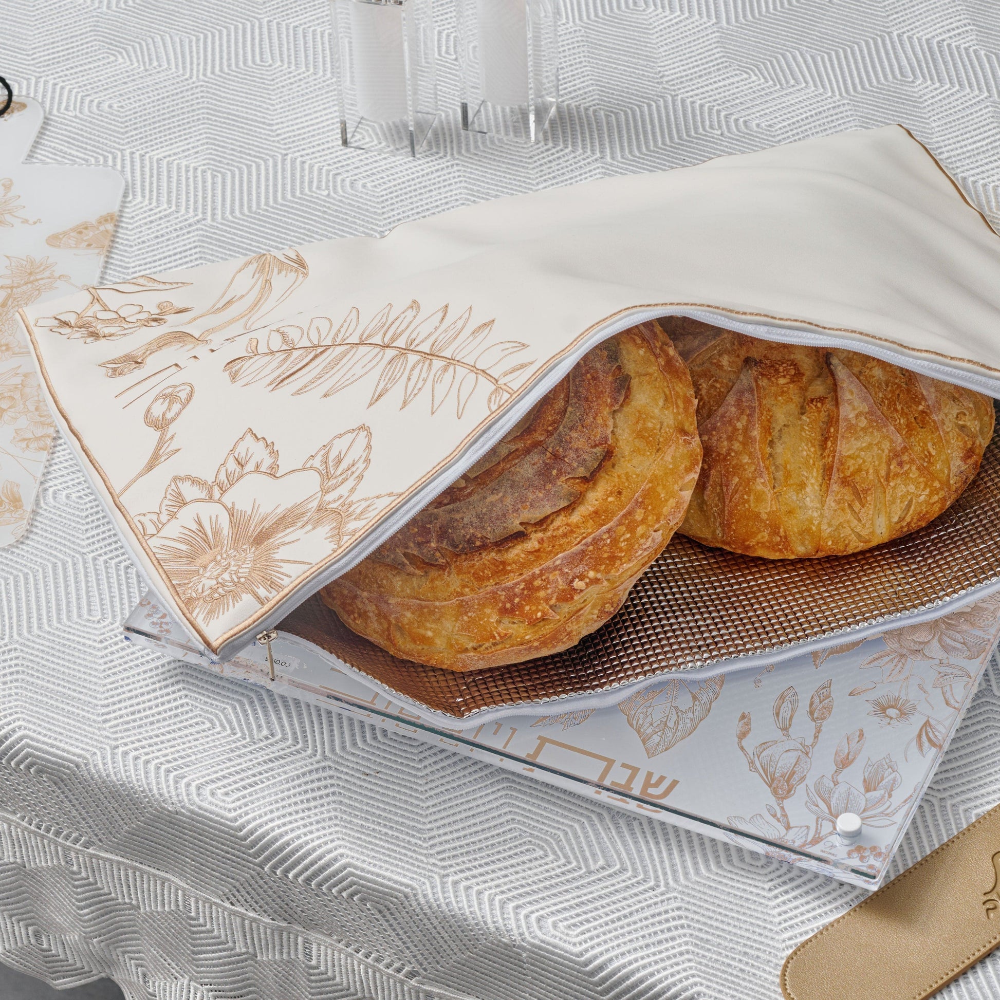 Freshly baked challah loaves wrapped in an Gold French Toile Challah Pouch Set.