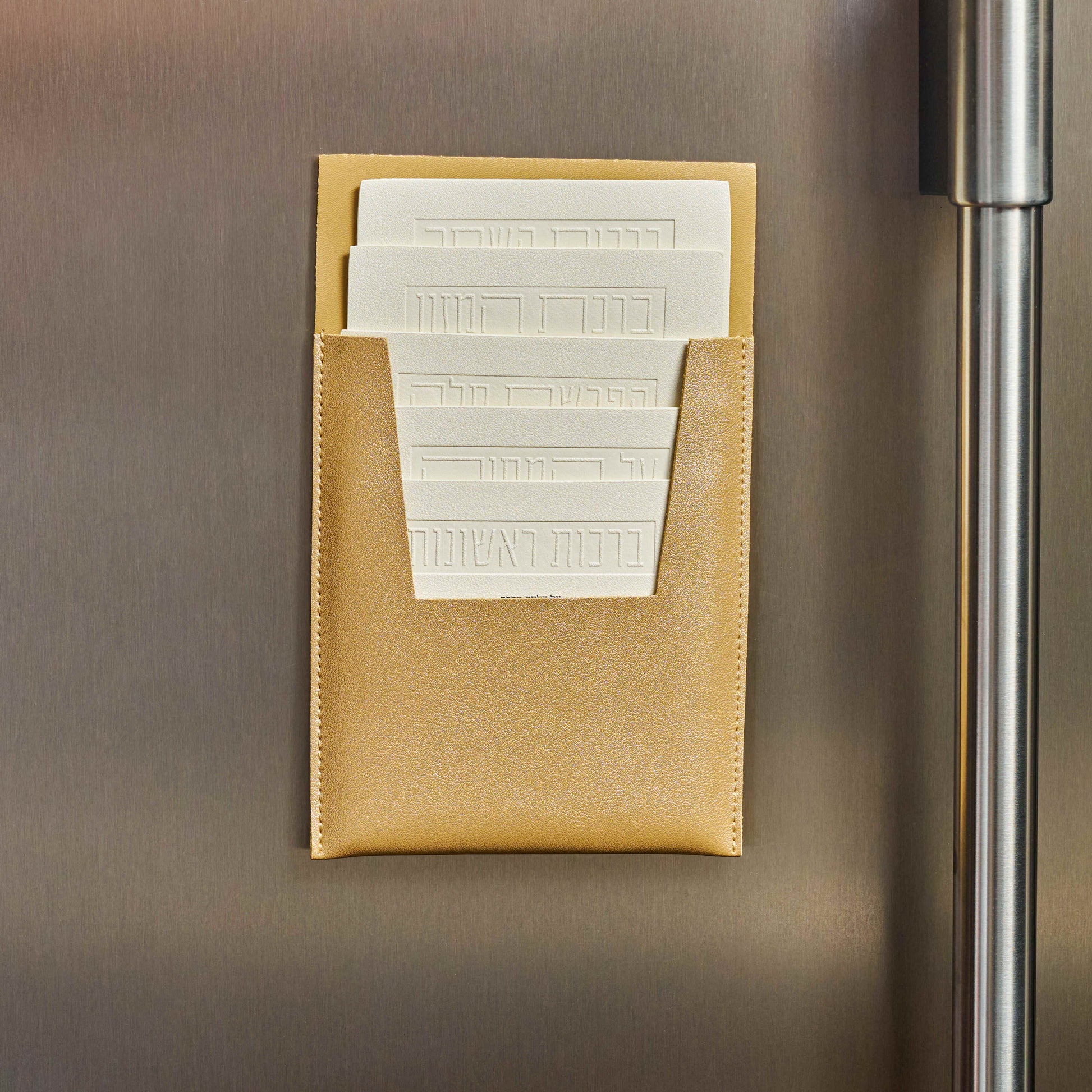 Close up photo of Gold Leather Magnetic Brachos Set on a refrigerator door