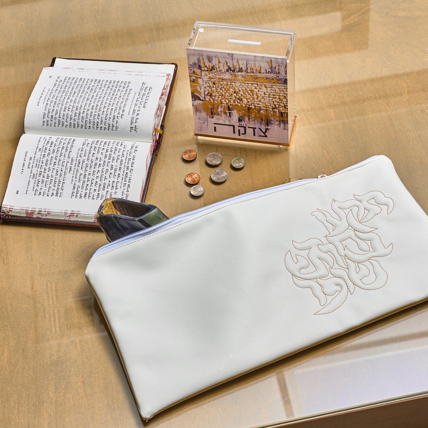 Leather Pillow Script Shofar Bag on a table with Painted by Judy Sculpture Kosel Tzedakah Box, and coins
