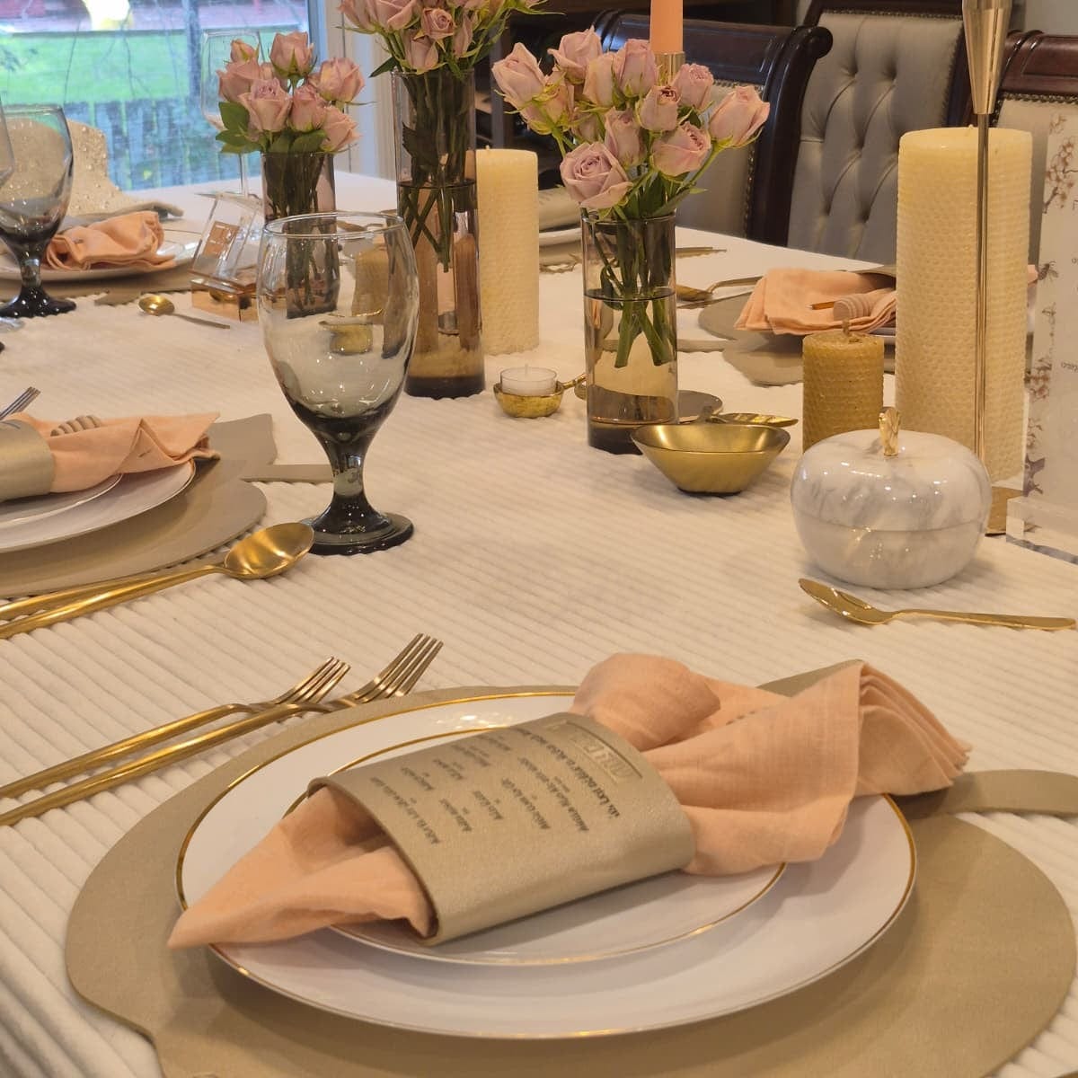 An elevated shot of a table setting featuring a Gold Leather Simanim Napkin Wrap on a white plate, leather gold apple charger and cutlery on Rosh Hashanah Tablescape