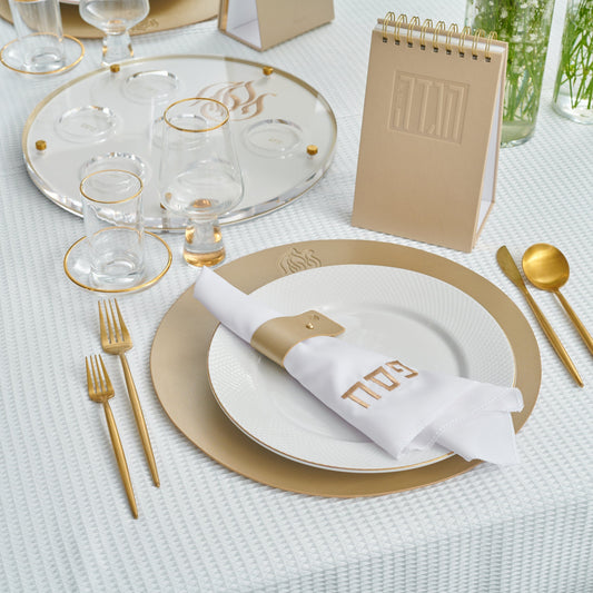 Pesach Leather Regal Round Chargers elegantly set on a white Pesach table with matching gold-accented tableware.