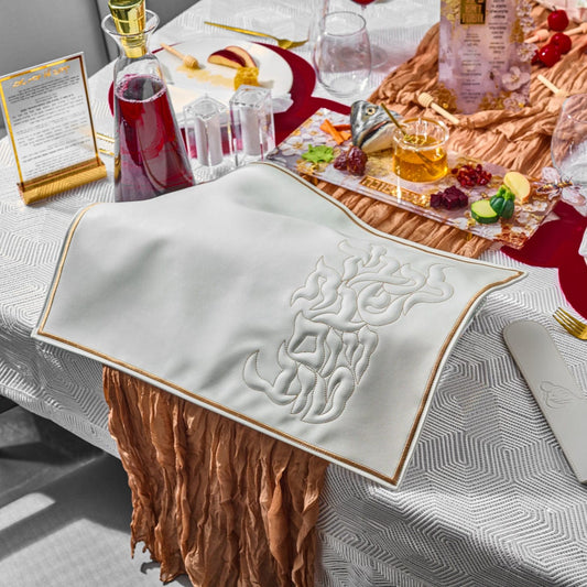Pillow Script Challah Cover on a festive Rosh Hashanah table set with wine, honey, pomegranates, and symbolic foods.
