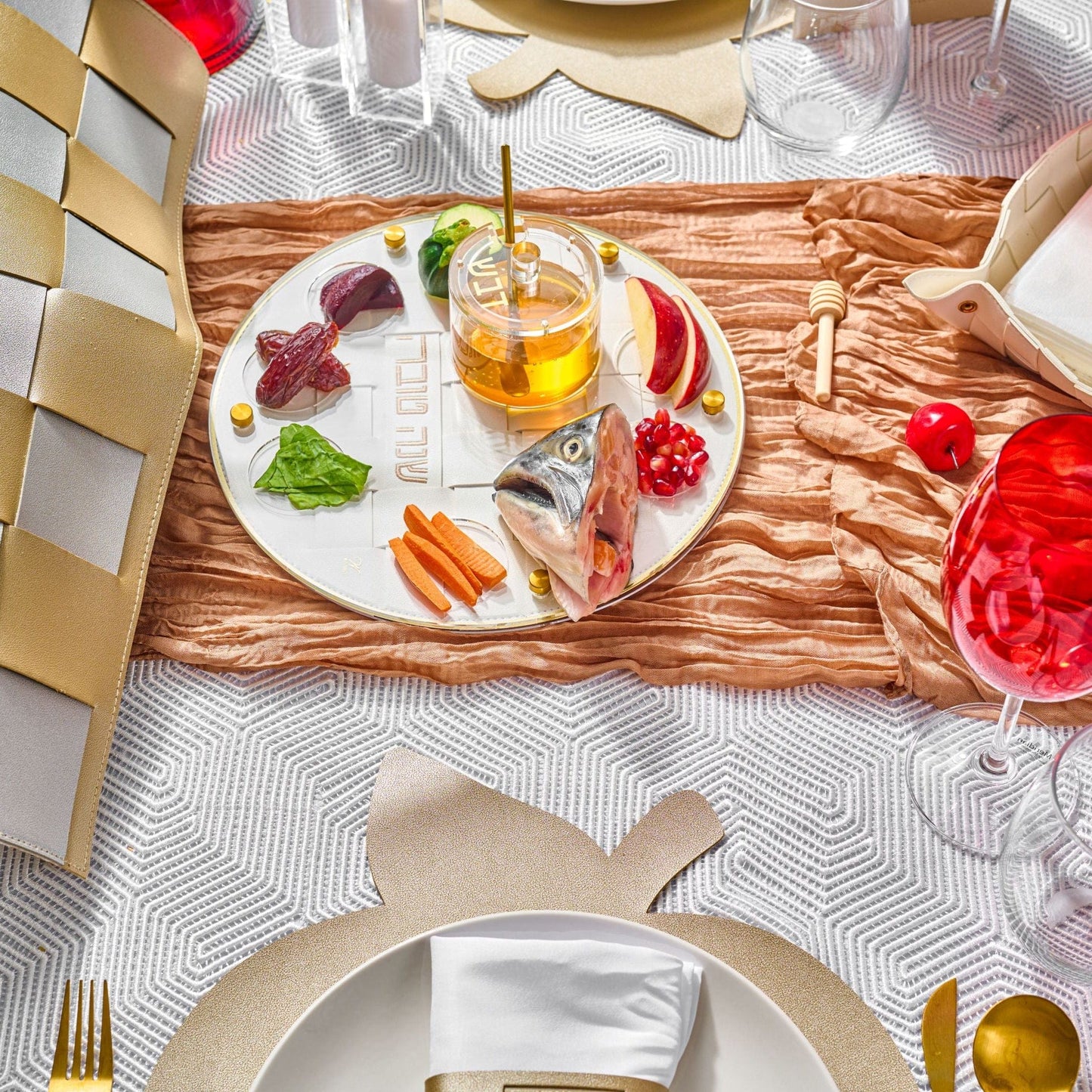 Gold Woven Simanim Tray with fish, honey dish, and other items on top of it in a Rosh Hashanah table setting
